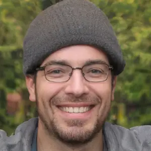 Smiling man wearing glasses and a gray knit beanie outdoors